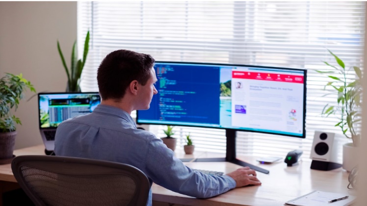 A guy develops software on his computer, sitting at his desk.